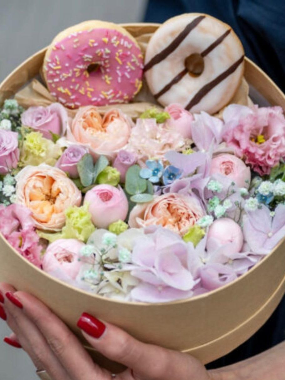Food und Blumen Ein Geschenkkorb mit Snacks, Bier und Süßigkeiten, dekoriert mit grünen Blättern.