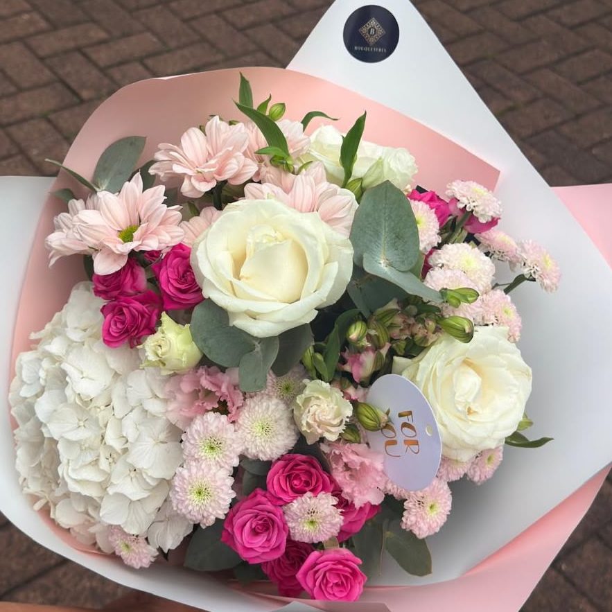 Ein üppiger Blumenstrauß mit Pfirsich- und weißen Rosen, Eukalyptus und zarten Akzenten.