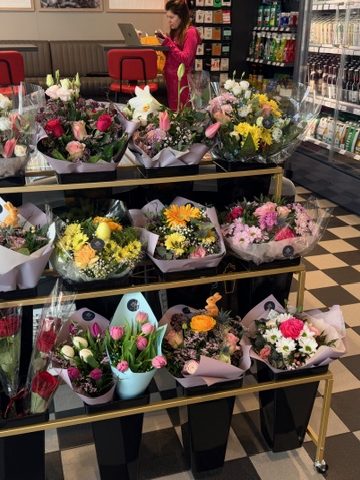 Shop in Shop Konzept für Blumen Eine Person in Rosa betrachtet verschiedene Blumensträuße in einem Geschäft.